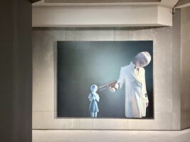 Obra de Gottfried Helnwein. Pintura. Niña vestida con uniforme militar apuntado a muñeca anime Fotografía Cristina Gala